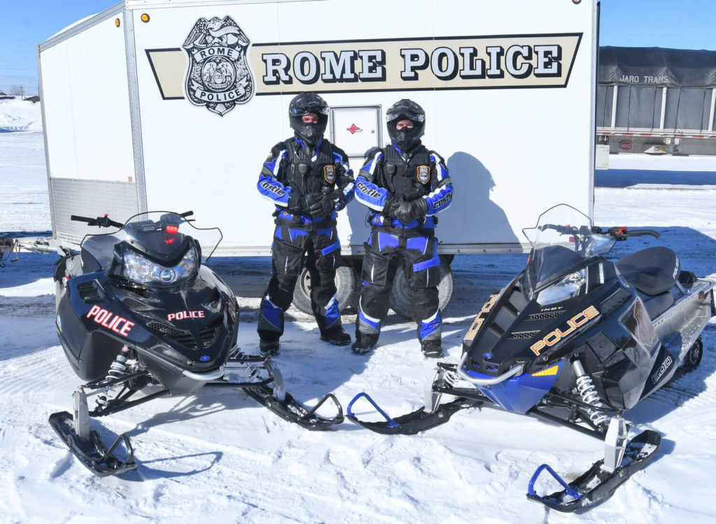 rome police department officers posing with snowmobiles in snow